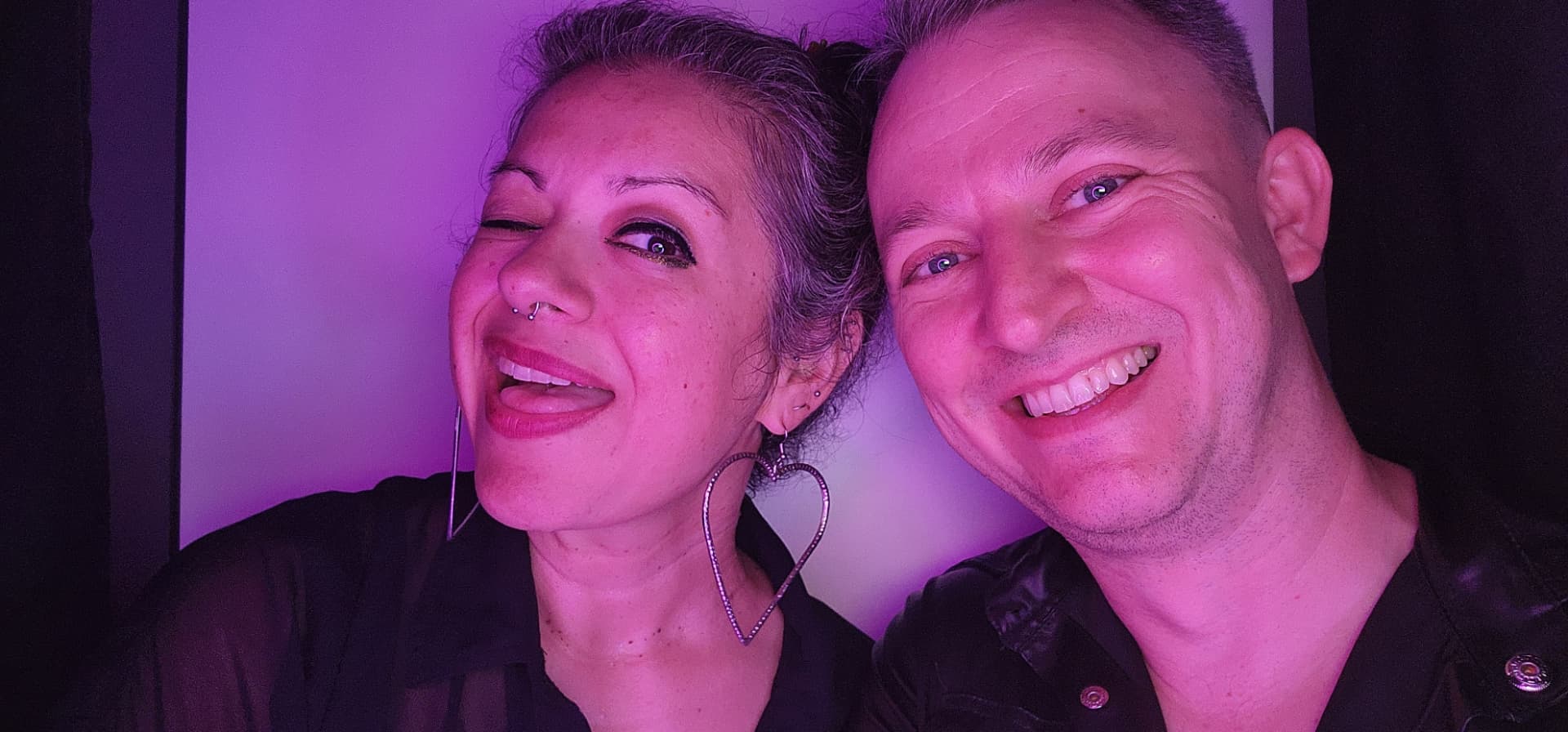A smiling couple enjoying the photo booth under purple event lighting